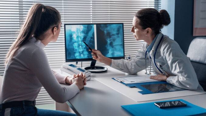 Professional doctor checking a patient's x-ray on the computer screen and pointing at the computer screen