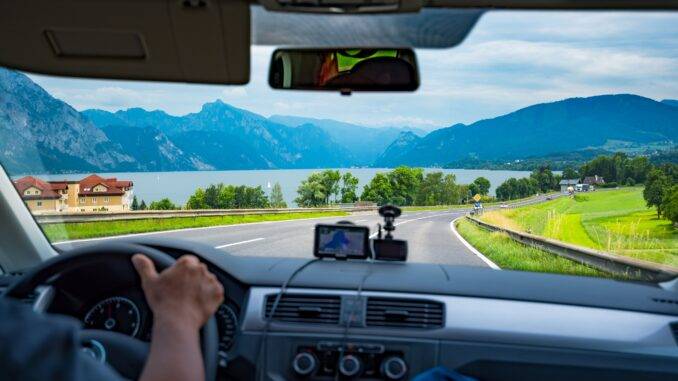 Die Perspektive eines Fahrers auf eine landschaftlich reizvolle Straße entlang eines Sees mit Bergen im Hintergrund, veranschaulicht die Bedeutung von WAB-Kursen in Winterthur für sicheres Fahren unter verschiedenen Bedingungen