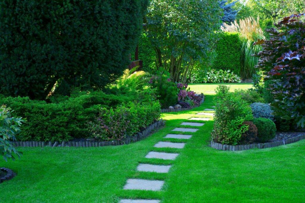 Gepflegter Garten mit grünem Weg und Gartenschildern