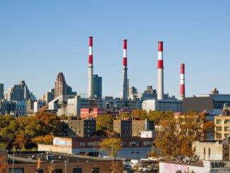 Industriegebäude mit Schornsteinen und Skyline im Hintergrund.