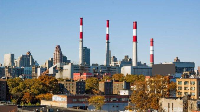 Industriegebäude mit Schornsteinen und Skyline im Hintergrund.