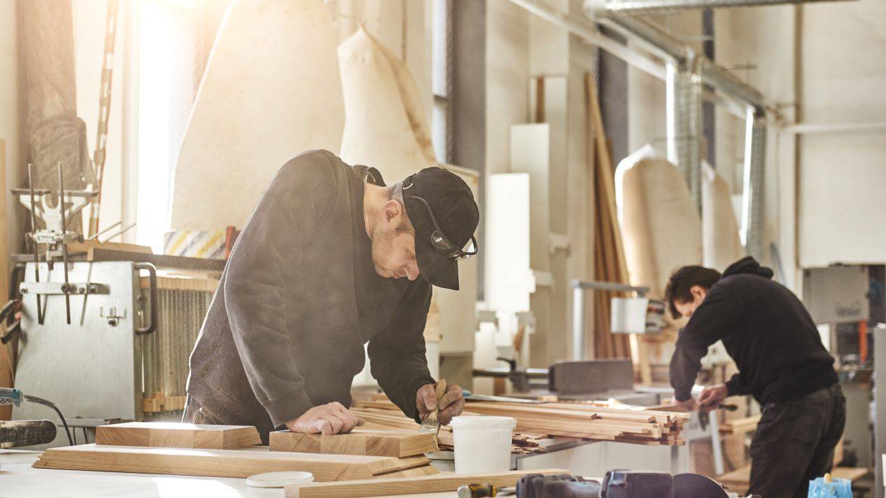 Zwei Tischler arbeiten konzentriert in einer Werkstatt an maßgefertigten Holzmöbeln, Möbelbau Berlin für individuelles Design und Qualität