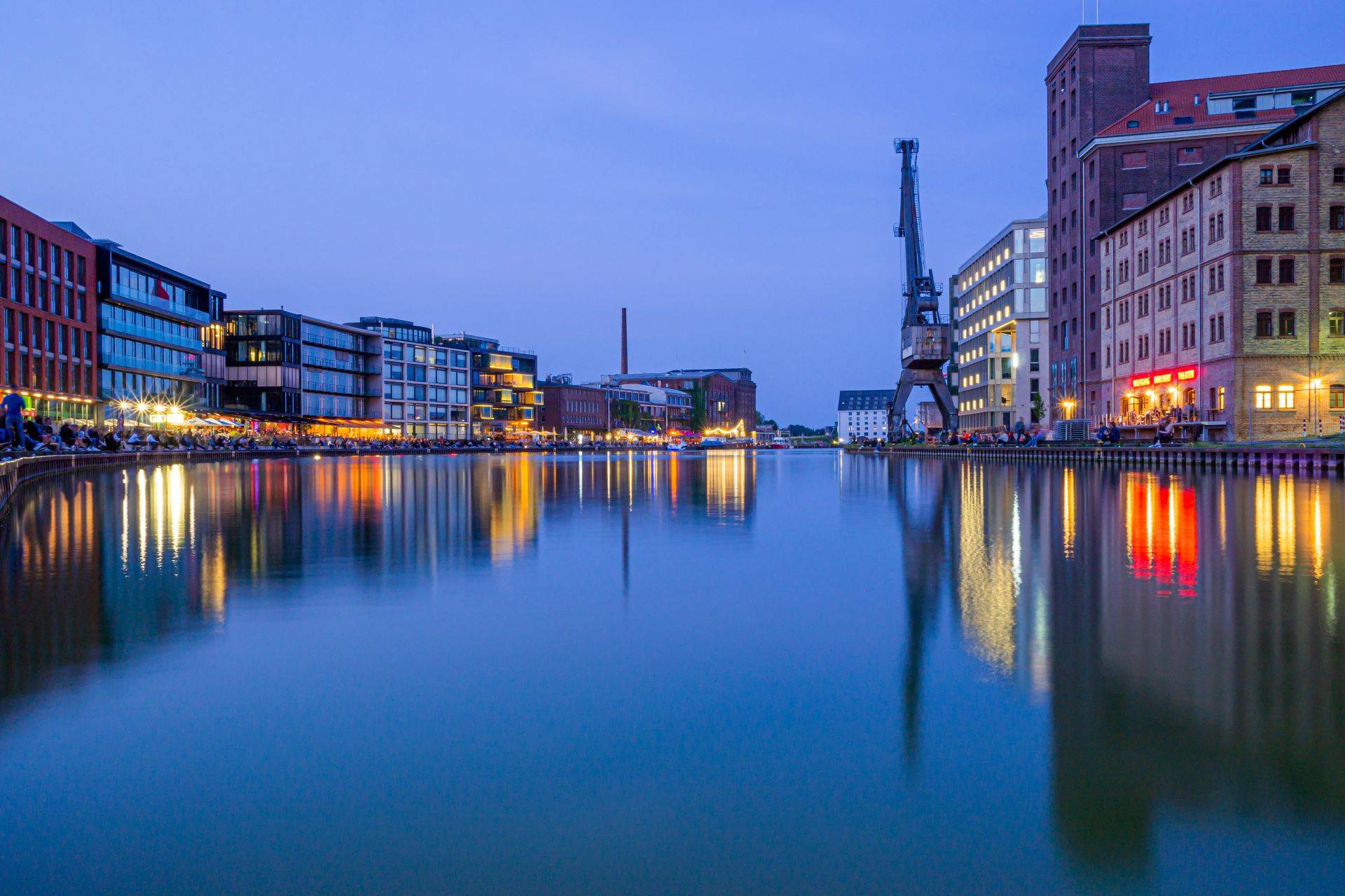 Hafenviertel von Münster bei Nacht mit stimmungsvoller Beleuchtung und Wasserreflexionen, ein idealer Ort für Begleitungen.