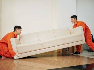 Zwei Umzugsprofis tragen gemeinsam ein Sofa durch eine Wohnung – Beispiel fuer koordinierten Umzugsservice in Erwitte.