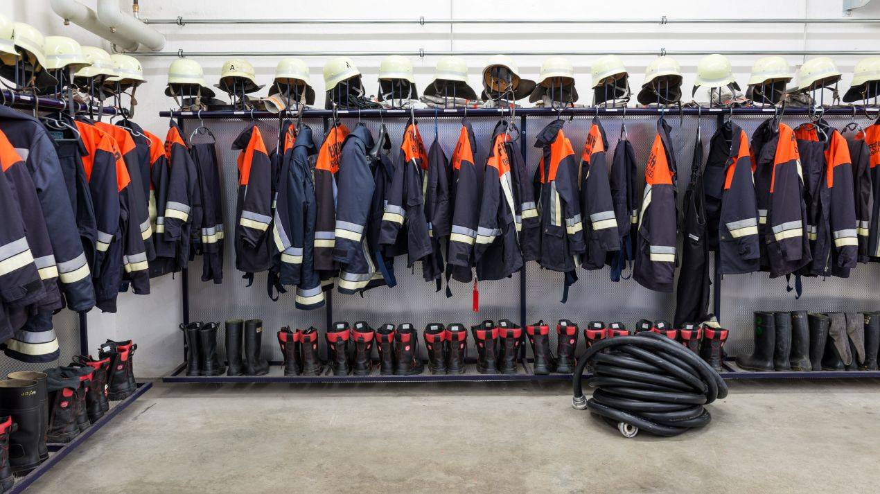 Feuerwehrschutzkleidung, Helme und Stiefel im Geraeteraum – Ausstattung fuer Brandwache in Hamburg vor dem Einsatz