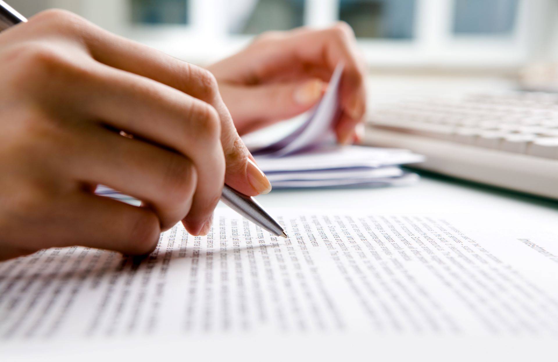 Hand markiert Textpassage mit Kugelschreiber