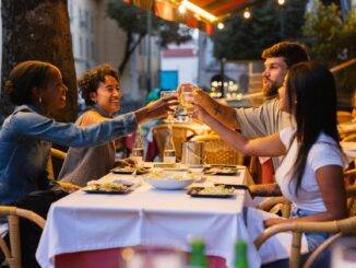 Freunde stoßen bei Abendstimmung in der Stadt mit Wein an