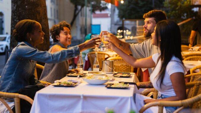 Freunde stoßen bei Abendstimmung in der Stadt mit Wein an