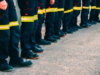 Reihe uniformierter Männer in Arbeitskleidung auf der Straße
