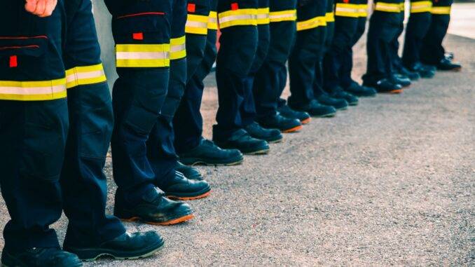 Reihe uniformierter Männer in Arbeitskleidung auf der Straße