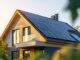 Nahaufnahme eines neuen Vorstadt Hauses mit einer Photovoltaikanlage auf dem Dach. Modernes, umweltfreundliches Passivhaus mit Solarpanelen auf dem Satteldach.
