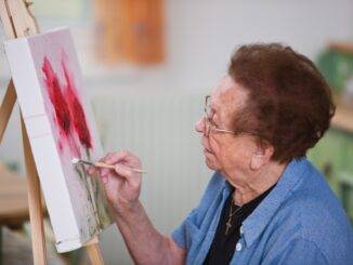 Ältere Frau malt konzentriert im Atelier | Inline Skates