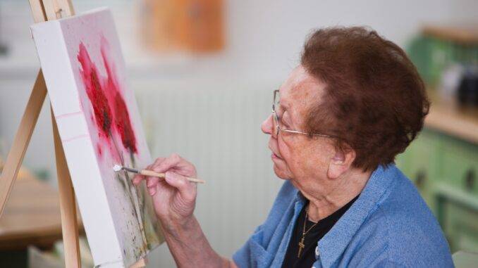 Ältere Frau malt konzentriert im Atelier | Inline Skates